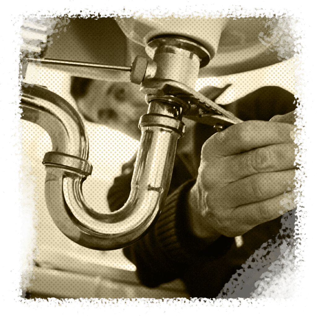 Plumber fixing broken pipe under sink